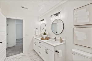 Full bathroom featuring double vanity, a textured ceiling, and light marble finish floors