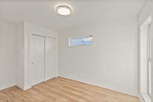 Unfurnished bedroom with a textured ceiling, light wood-type flooring, and a closet