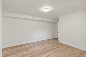 Empty room featuring a textured ceiling and light wood finished floors