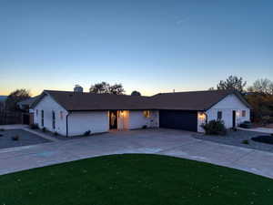 Ranch-style home with driveway, an attached garage, and a chimney