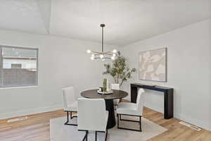 Dining area with a chandelier, a textured ceiling, and light wood-style flooring