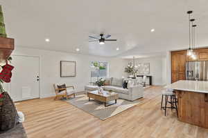Living area featuring recessed lighting, light wood-type flooring, lofted ceiling, a ceiling fan, and a chandelier