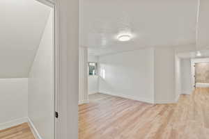 Additional living space with a textured ceiling and light wood-style flooring