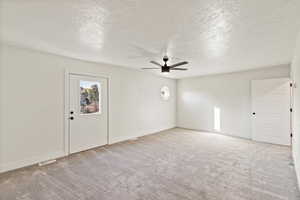 Unfurnished room with a textured ceiling, light colored carpet, and a ceiling fan