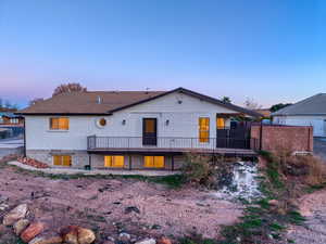 Rear view of house featuring a wooden deck, brick siding, and a patio area