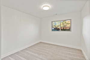 Spare room with a textured ceiling and light carpet