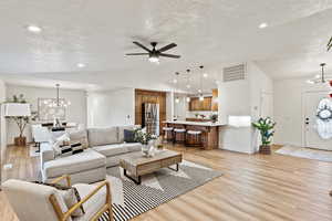 Living room featuring a chandelier, a textured ceiling, recessed lighting, lofted ceiling, and ceiling fan