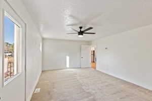 Unfurnished room featuring light carpet, a textured ceiling, and ceiling fan