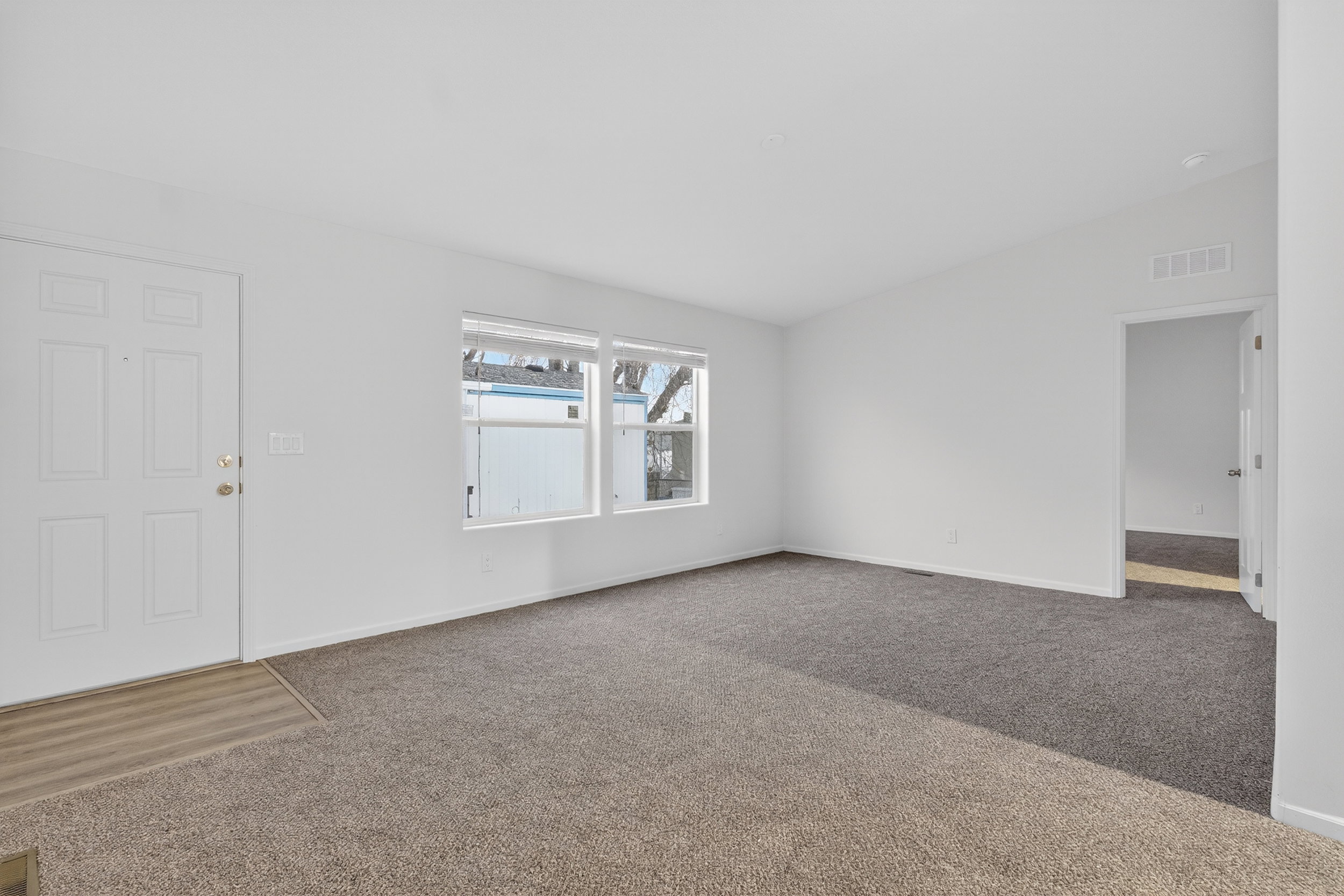 Carpeted spare room featuring vaulted ceiling and baseboards