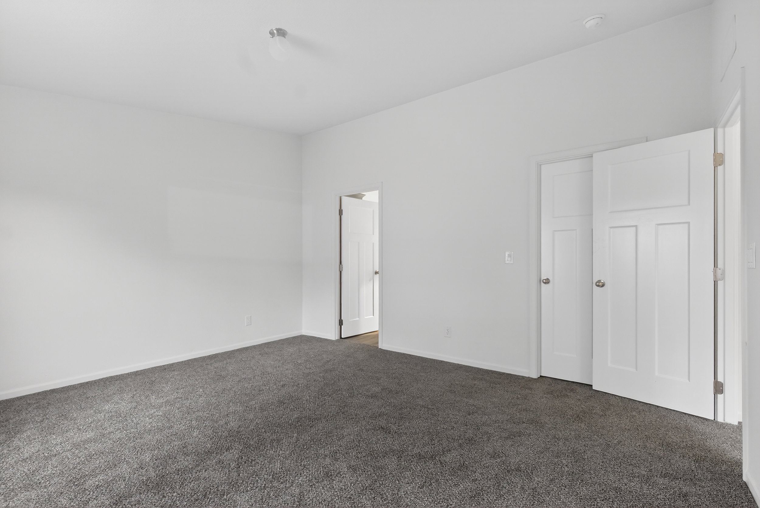 Unfurnished bedroom with dark carpet and baseboards