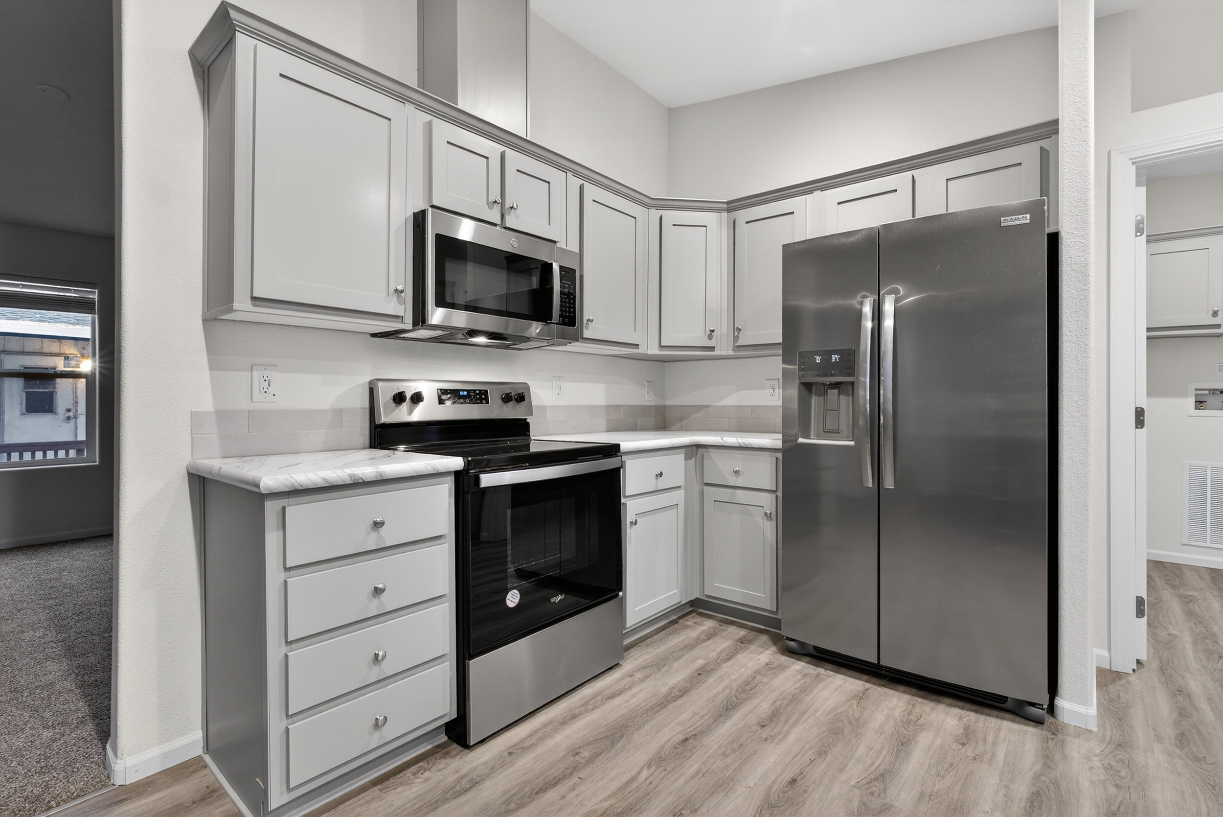Kitchen with appliances with stainless steel finishes, gray cabinetry, and light countertops