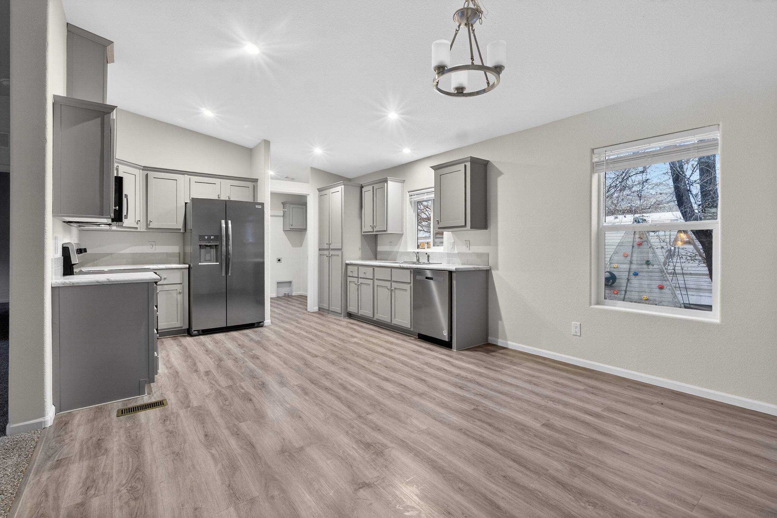 Kitchen with gray cabinetry, appliances with stainless steel finishes, lofted ceiling, recessed lighting, and light wood finished floors