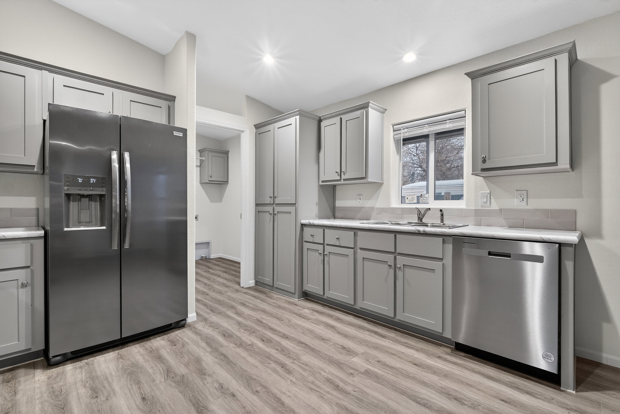 Kitchen with gray cabinets, stainless steel appliances, light wood-type flooring, and recessed lighting