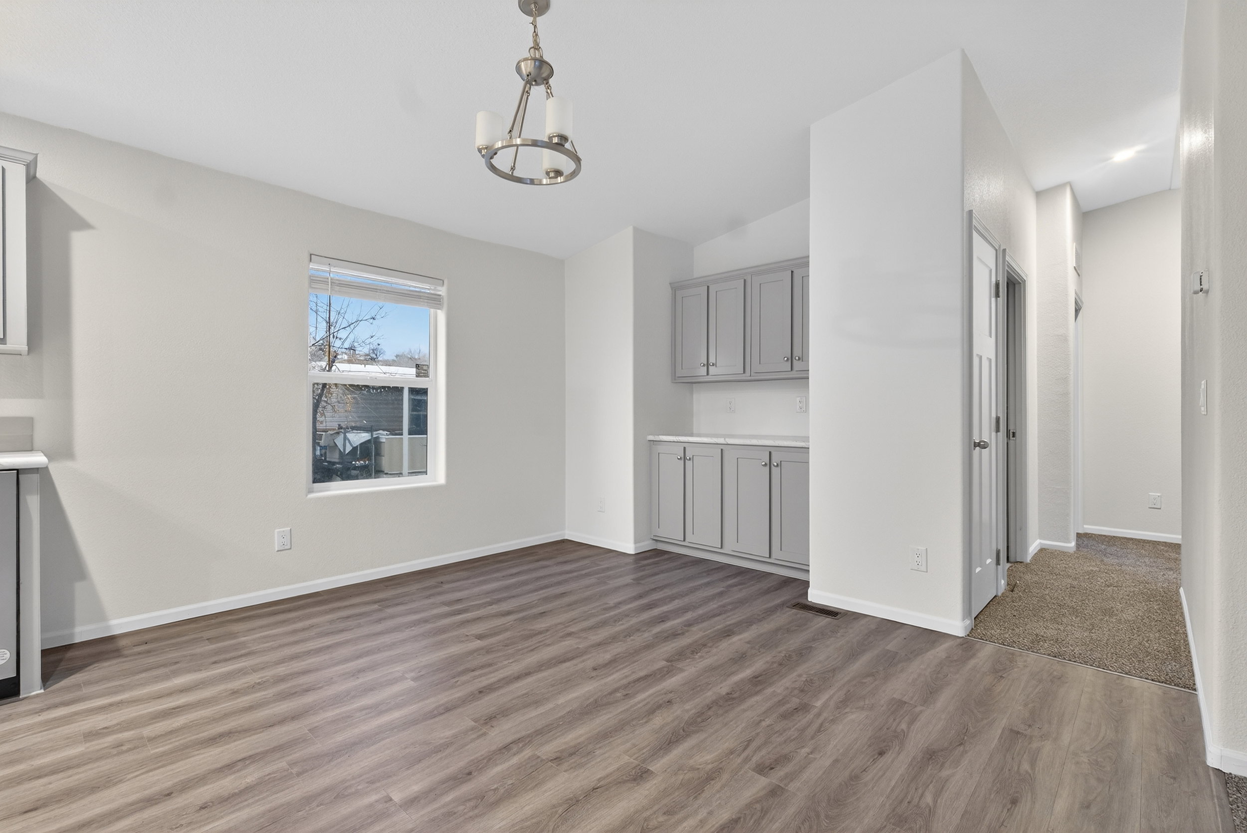 Unfurnished living room featuring wood finished floors, a chandelier, and lofted ceiling