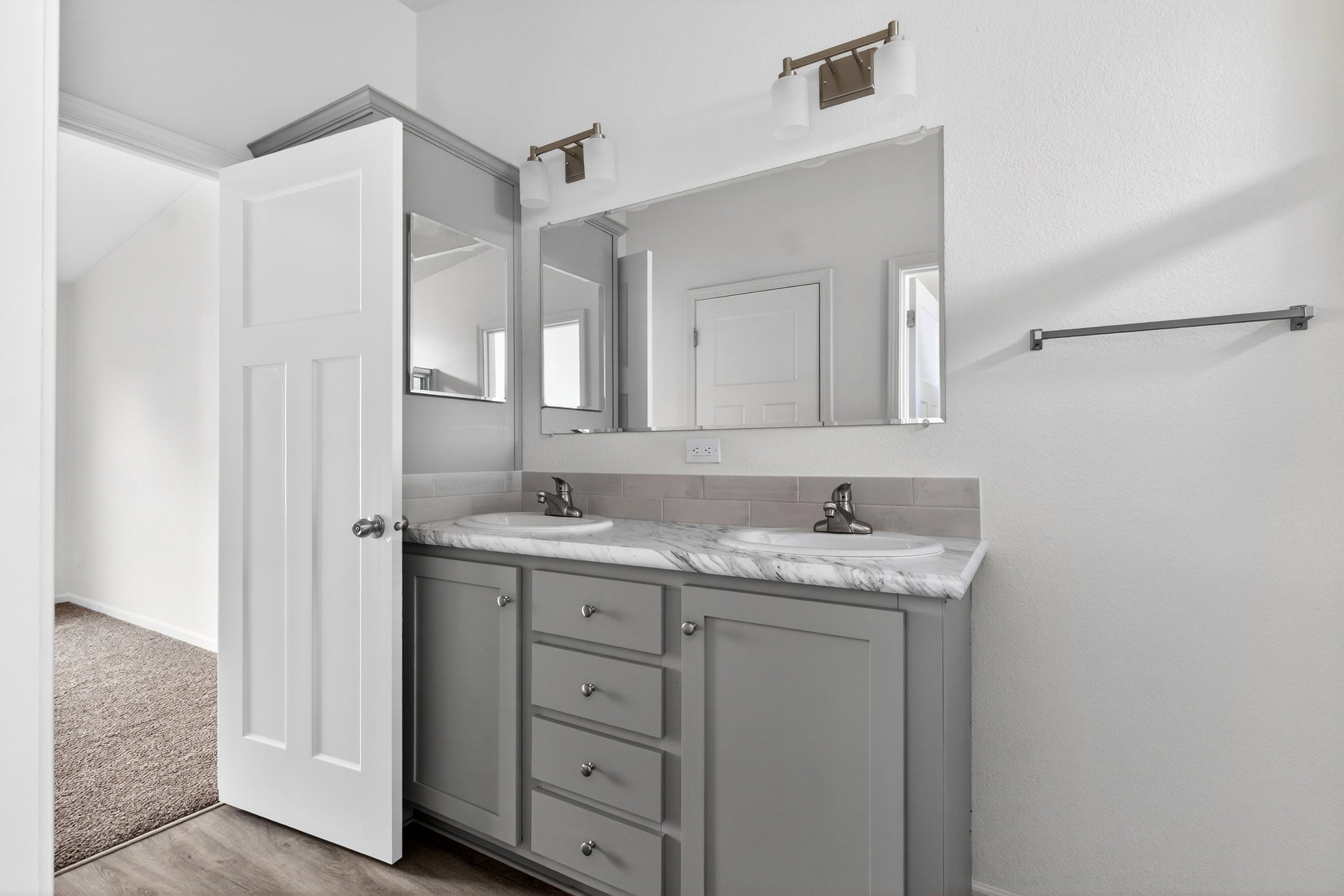 Bathroom with double vanity and light wood-type flooring
