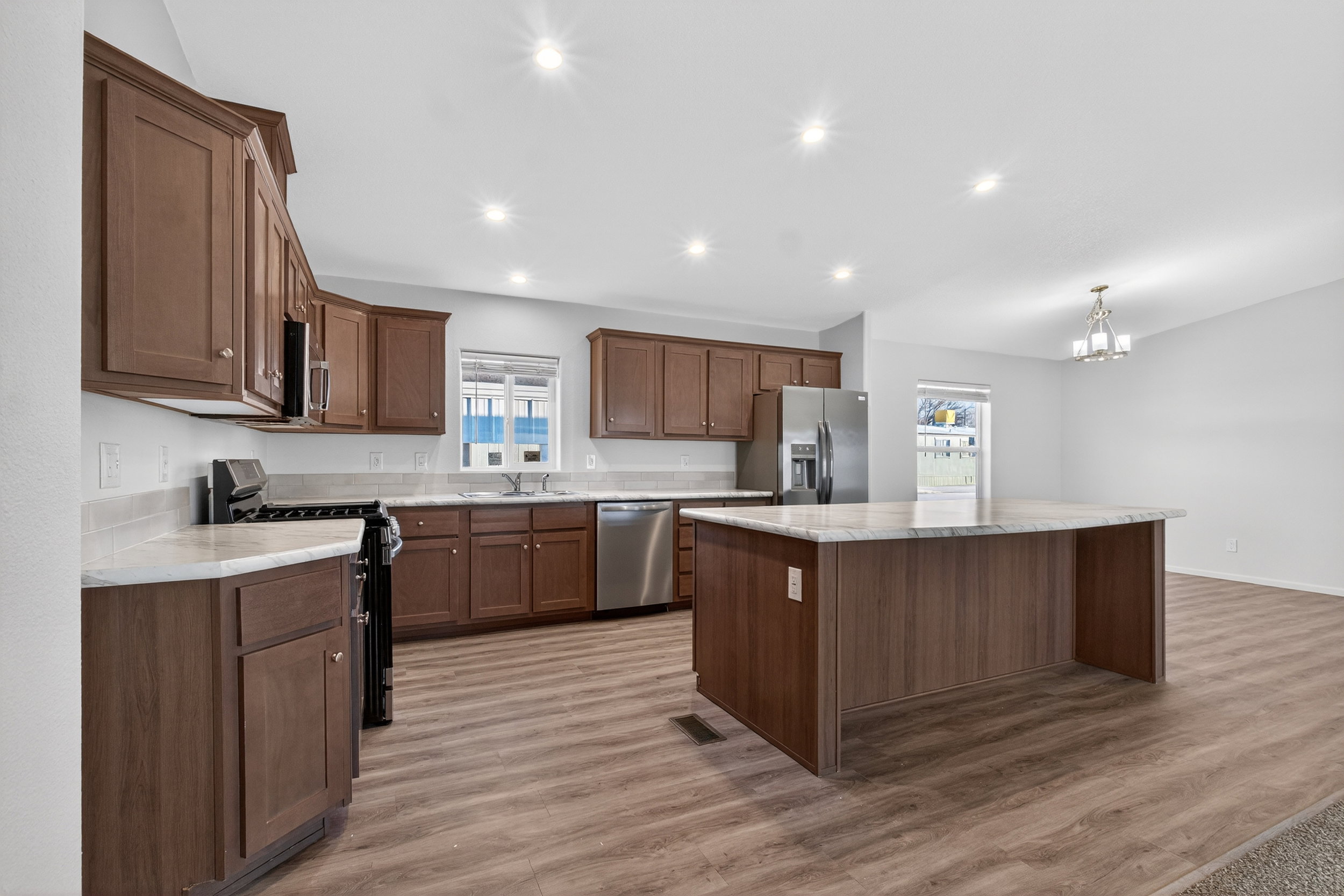 Kitchen with stainless steel appliances, a center island, a chandelier, recessed lighting, and light wood-style flooring