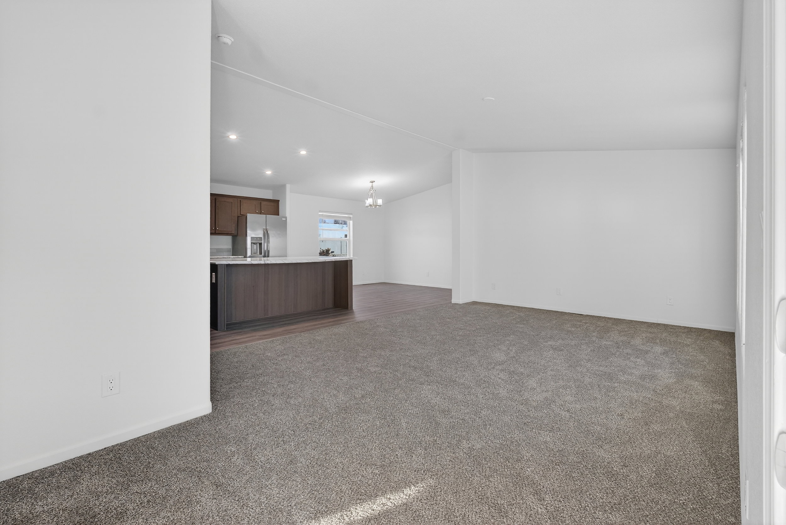 Unfurnished living room with dark carpet, vaulted ceiling, a chandelier, and recessed lighting
