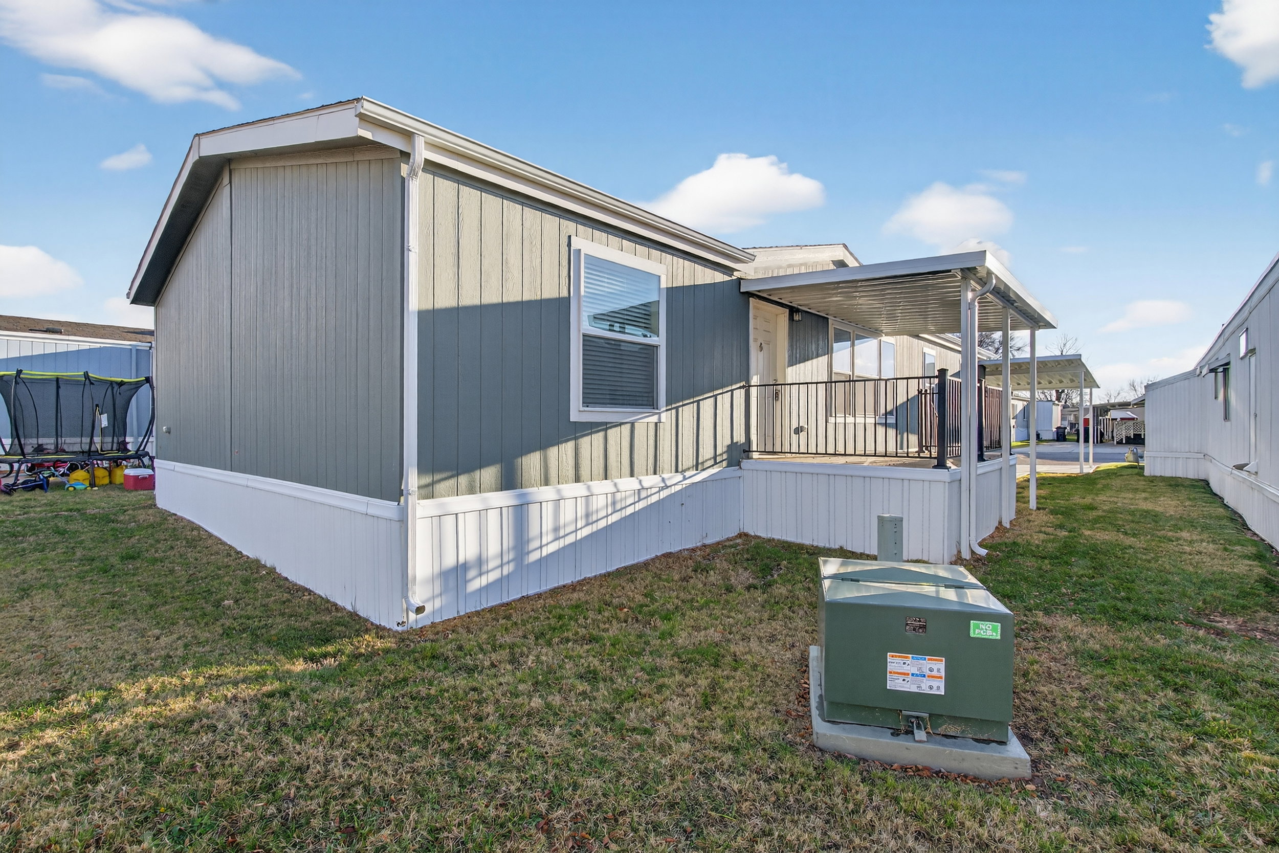 View of side of home featuring a trampoline and a lawn
