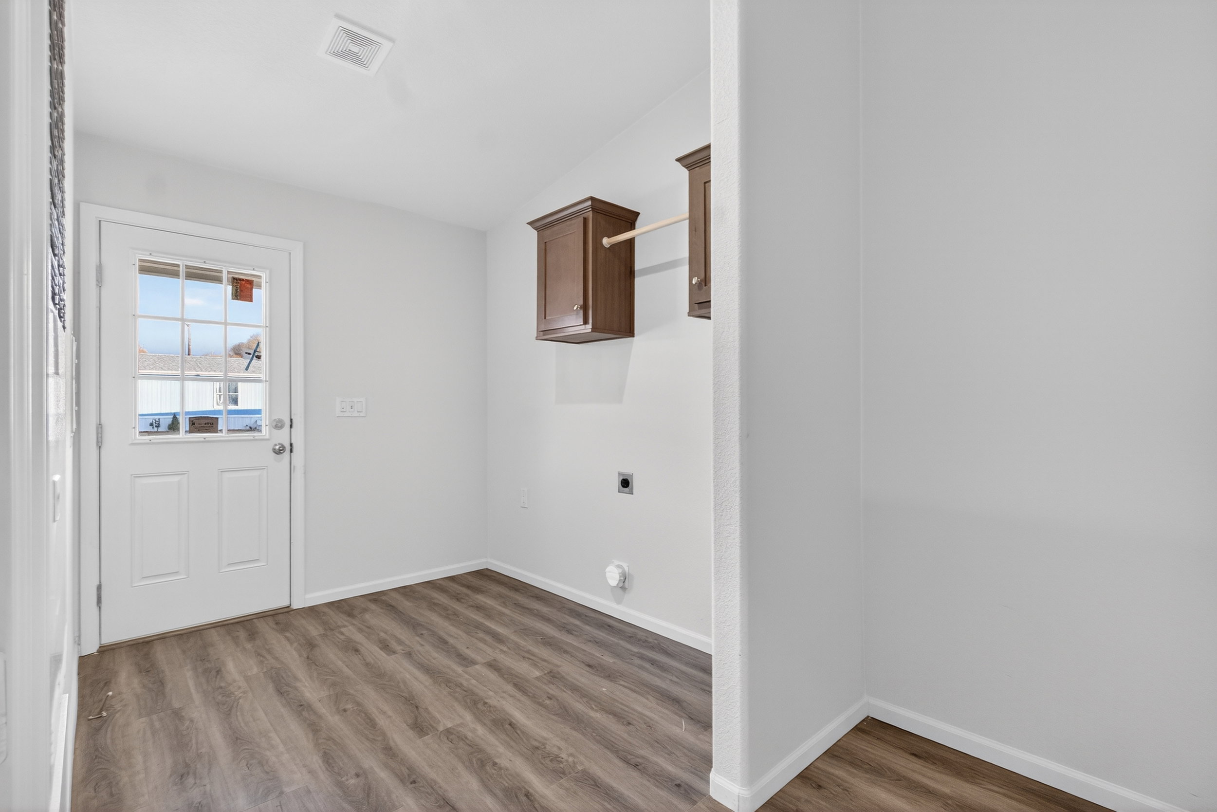 Laundry room with electric dryer hookup, light wood-type flooring, and cabinet space