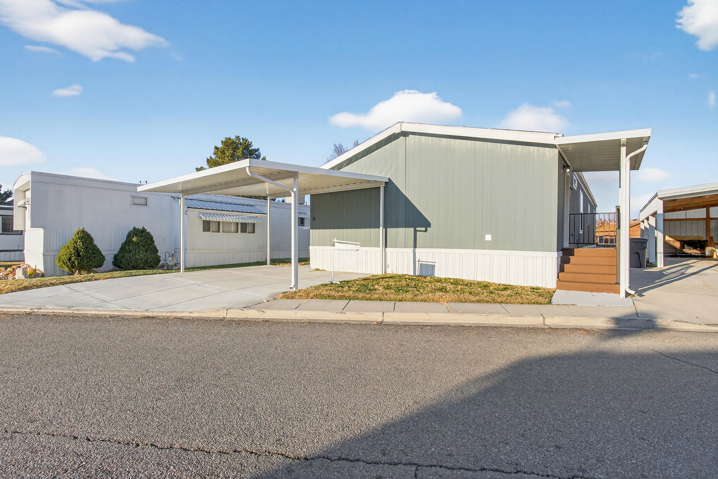 Manufactured / mobile home with concrete driveway and a carport