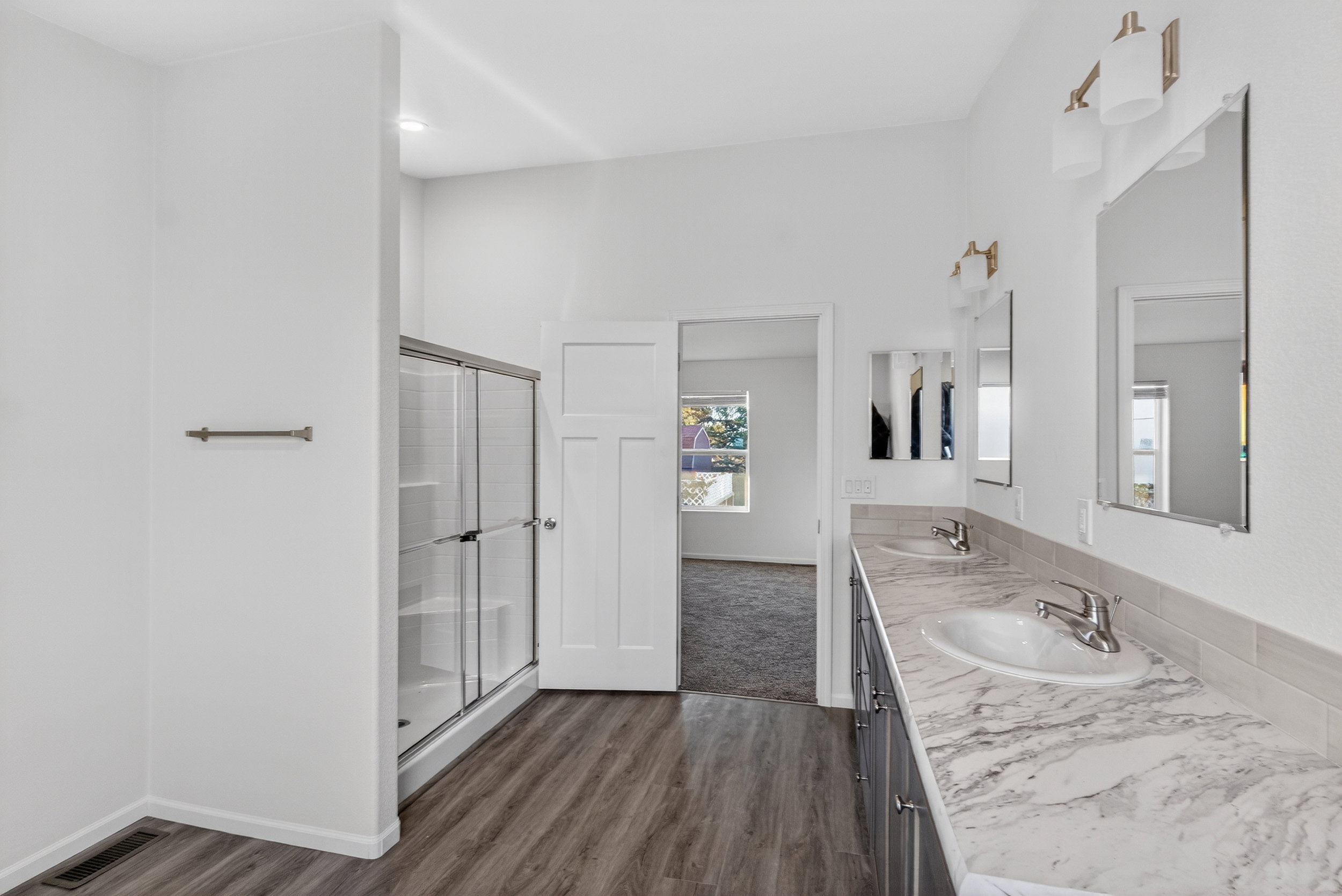 Full bathroom with double vanity, dark wood-type flooring, and a stall shower