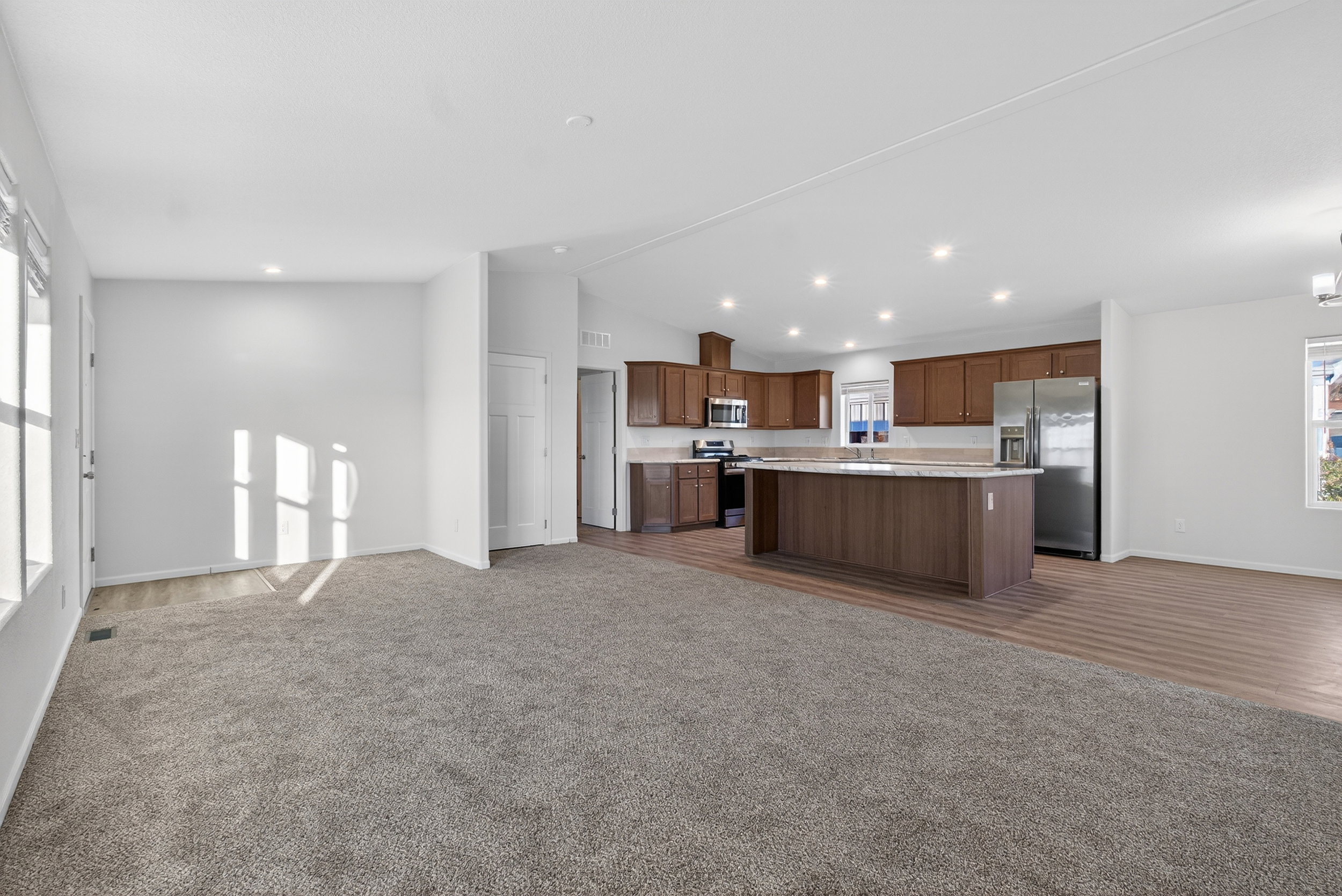 Kitchen with open floor plan, light countertops, dark colored carpet, appliances with stainless steel finishes, and lofted ceiling