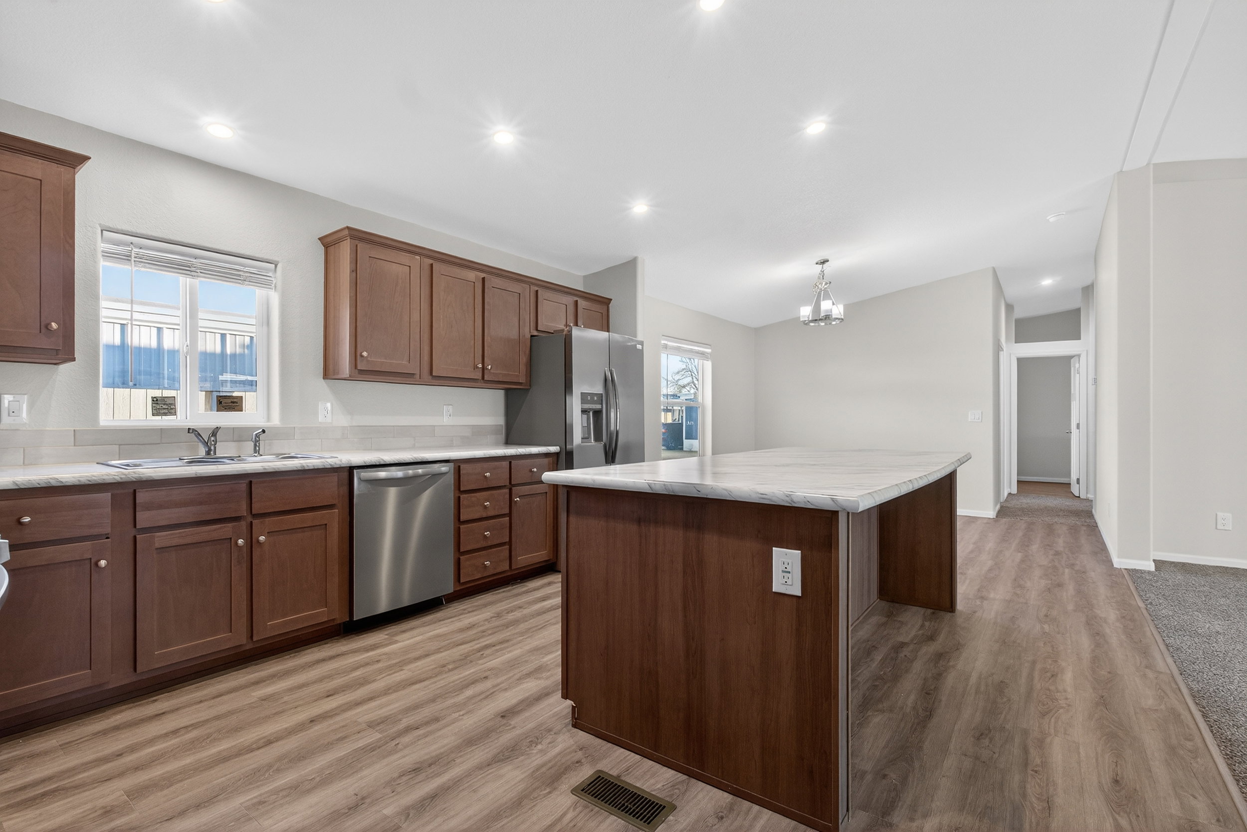 Kitchen with a center island, appliances with stainless steel finishes, a chandelier, light wood-style flooring, and recessed lighting