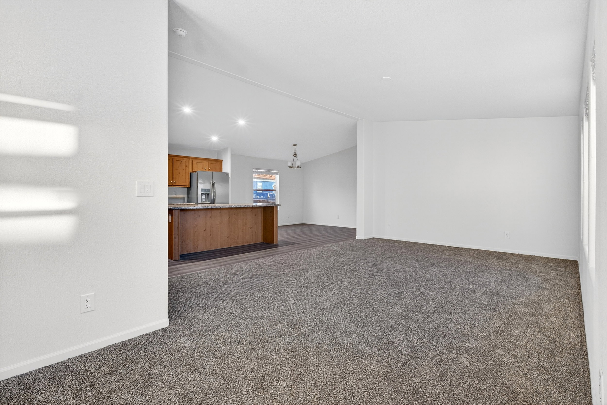 Unfurnished living room featuring vaulted ceiling, dark colored carpet, and recessed lighting