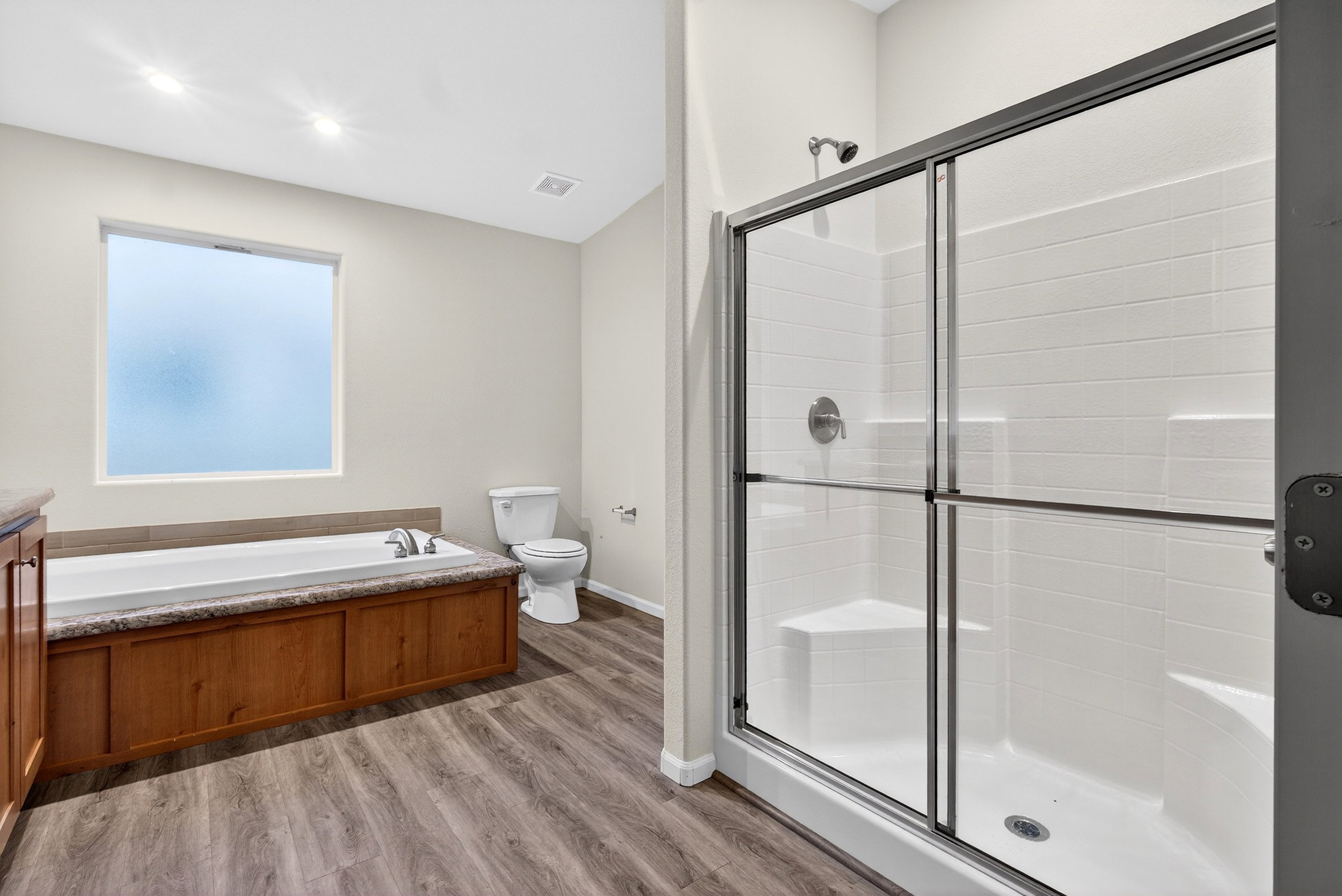 Bathroom with a stall shower, vanity, a bath, and light wood-style flooring