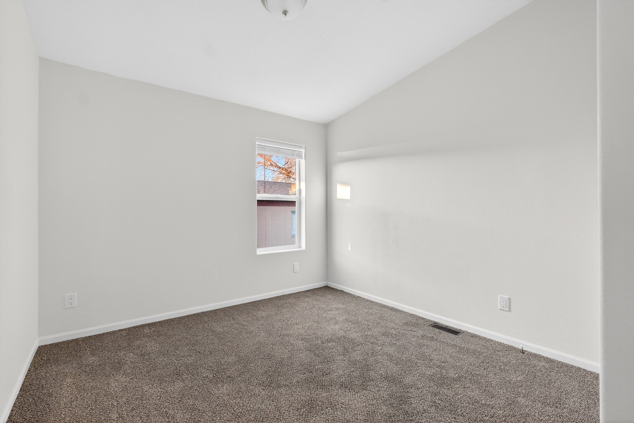 Empty room featuring vaulted ceiling and carpet flooring