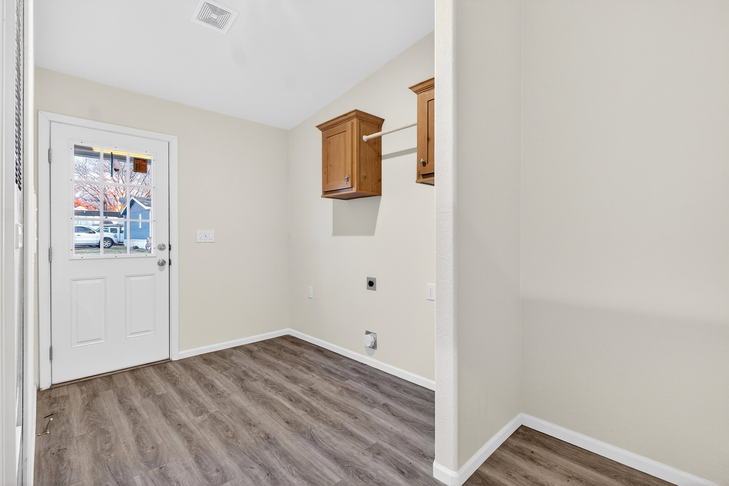 Laundry area featuring hookup for an electric dryer, wood finished floors, and cabinet space