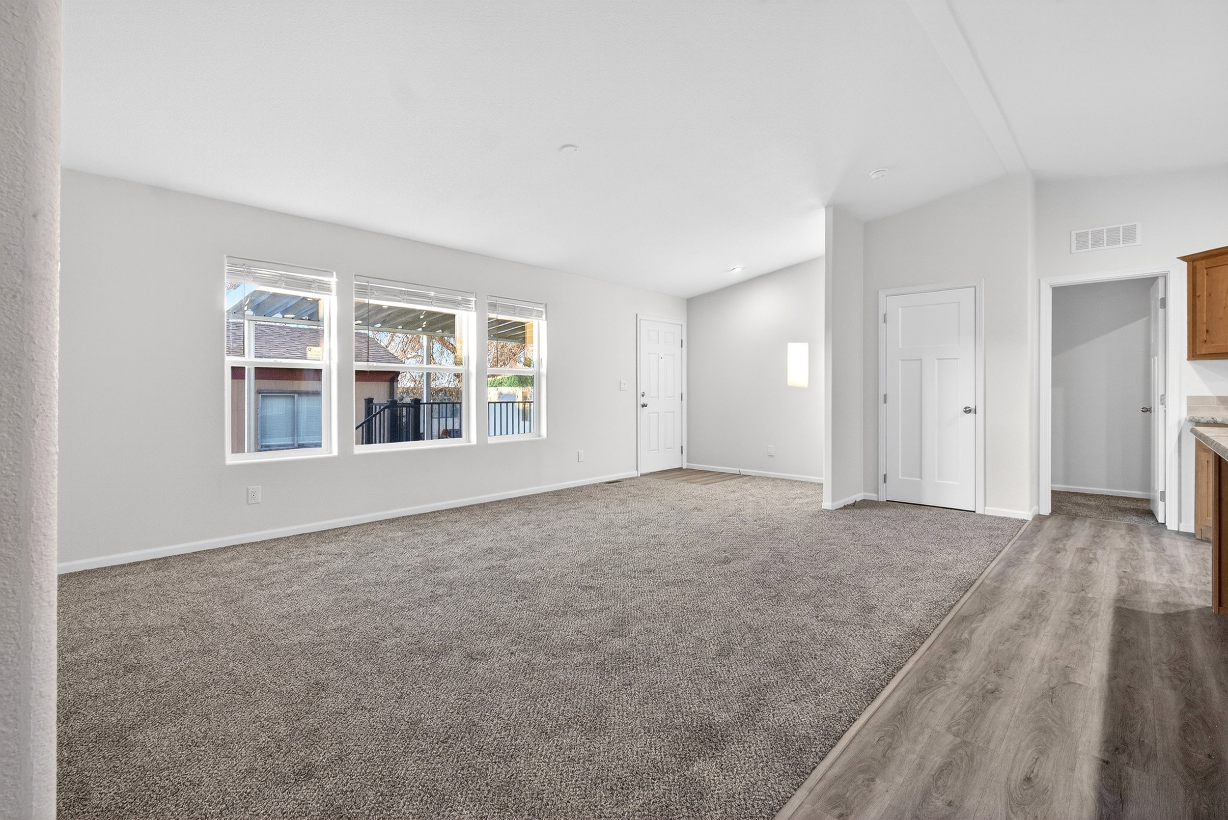 Unfurnished living room featuring vaulted ceiling, dark colored carpet, and dark wood-style flooring