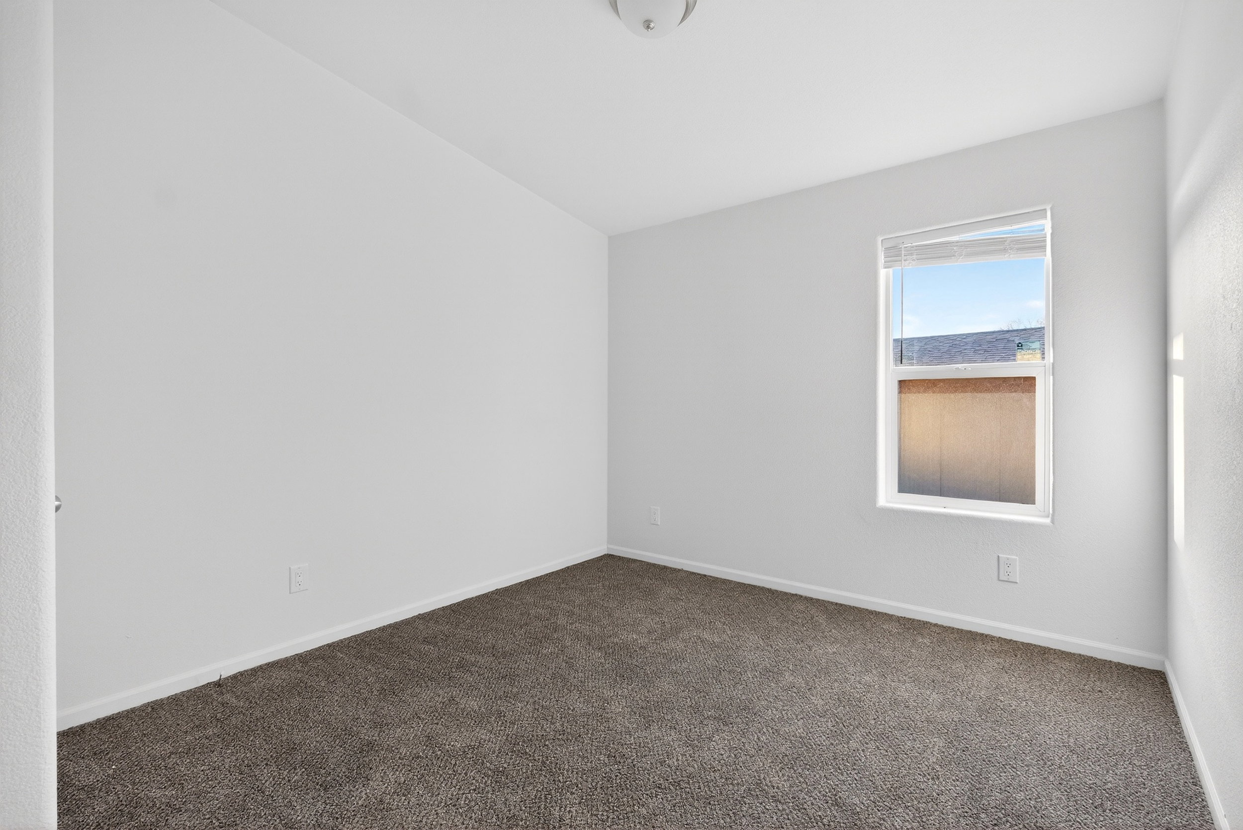 Spare room featuring dark carpet and baseboards