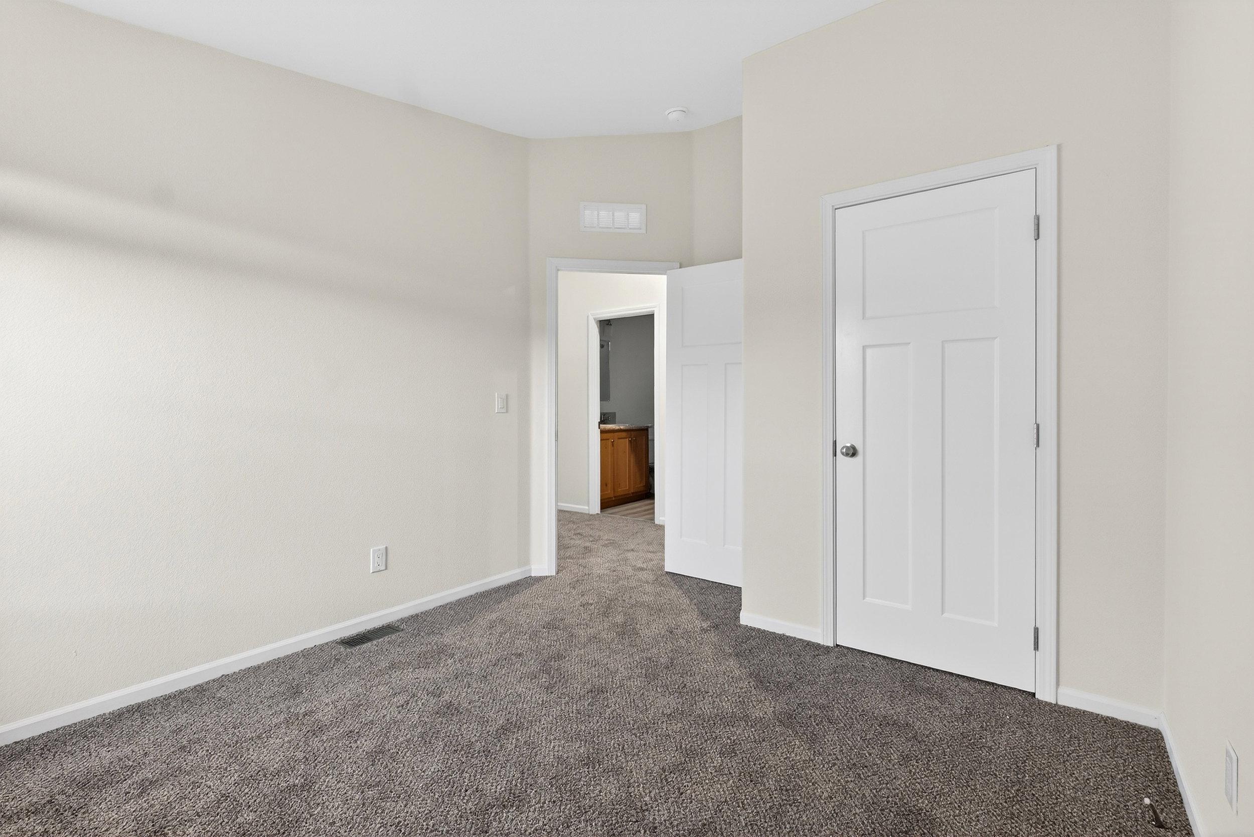 Unfurnished bedroom with dark carpet and baseboards