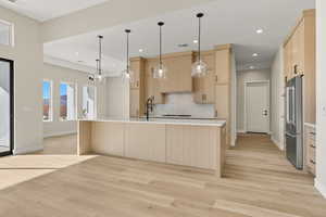 Kitchen featuring light brown cabinets, high end fridge, decorative light fixtures, light wood finished floors, and recessed lighting