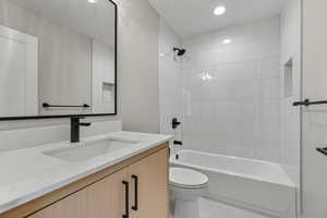 Bathroom with bathtub / shower combination, vanity, and recessed lighting