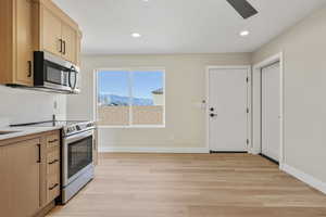 Kitchen featuring appliances with stainless steel finishes, light brown cabinetry, light wood finished floors, recessed lighting, and light stone counters
