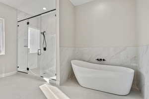 Bathroom with a marble finish shower, a freestanding tub, tile walls, tile patterned flooring, and wainscoting