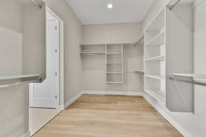 Walk in closet with light wood-style floors