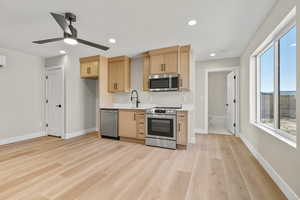 Kitchen with appliances with stainless steel finishes, light brown cabinets, light wood finished floors, recessed lighting, and ceiling fan