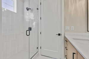 Full bathroom with vanity, a stall shower, and light tile patterned floors