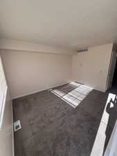 Carpeted spare room with baseboards and a textured ceiling