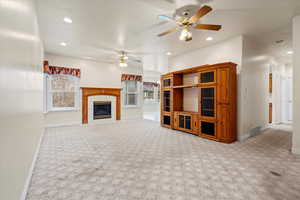 Unfurnished living room featuring recessed lighting, light colored carpet, a fireplace, ceiling fan, and arched walkways