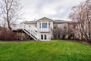 Back of house with stairs, a lawn, french doors, and a deck