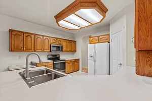 Kitchen with brown cabinetry, appliances with stainless steel finishes, light countertops, and light tile patterned flooring