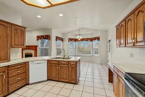 Kitchen with brown cabinets, dishwasher, light countertops, a peninsula, and lofted ceiling