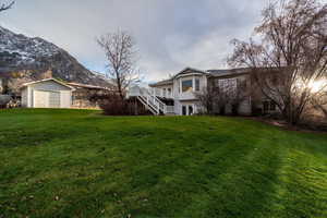 View of grassy yard featuring stairway, an outdoor structure, and a deck