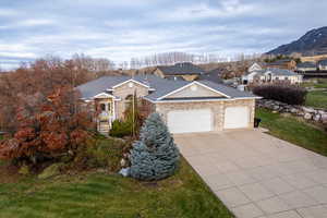 Single story home featuring a front yard, driveway, a garage, stone siding, and a residential view