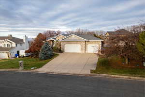 View of front facade with concrete driveway, a garage, stone siding, a residential view, and a front yard