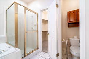 Bathroom with a bath, a walk in closet, a stall shower, and light tile patterned floors
